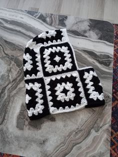 a black and white crocheted hat sitting on top of a marble countertop