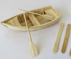 a wooden boat with oars and paddles on a white surface next to it