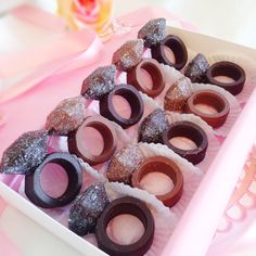 a box filled with donuts on top of a pink tablecloth covered table cloth