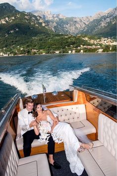 a bride and groom sitting on the back of a boat