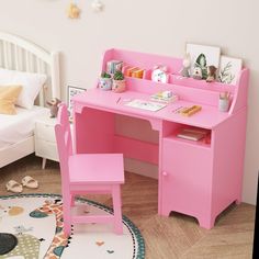 a child's pink desk and chair in a room with a white bed behind it