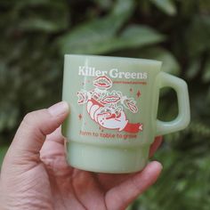 a hand holding a green coffee cup with an image of a santa clause on it