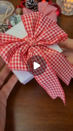 someone is holding a present wrapped in red and white checkered paper with a bow