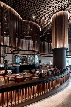 the interior of a restaurant with wooden tables and chairs, along with round wood columns