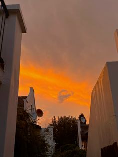 an orange and yellow sky is seen from between two buildings