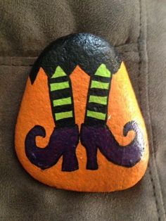 an orange and black painted rock with two legs in the shape of a moustache