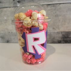 a plastic container filled with pink and white candy corn, next to a sign that reads r