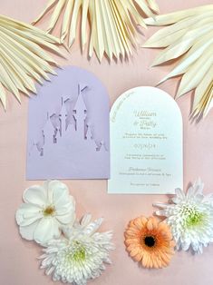 the wedding stationery is laid out with flowers and palm leaves