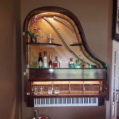 an old piano with many bottles and glasses on it's shelf above the piano