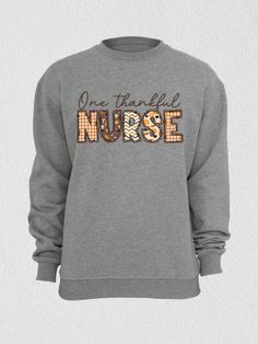 Introducing our "One Thankful Nurse Mama" T-shirt, a delightful addition to your autumn wardrobe!  Express your gratitude as both a nurse and a mama with this charming design.  This shirt features a hand-drawn illustration of a pumpkin, symbolizing the fall season and the joy of Thanksgiving. The pumpkin is adorned with a nurse's cap, showcasing your dedication to the nursing profession.  Designed for both comfort and style, our shirt is crafted from soft and breathable fabric, ensuring a cozy f Fall Nursing Sweatshirt With Crew Neck, Fall Crew Neck Nursing Top, Cotton Sweatshirt For Nursing In Fall, Cotton Nursing Sweatshirt For Fall, Thankful Mama Shirt, Funny Nurse Shirts, Nursing Profession, Thankful Shirt, New Nurse