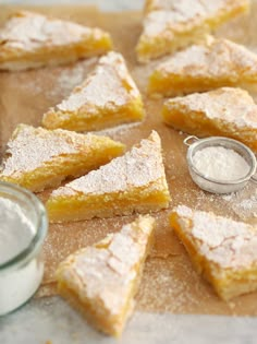 several pieces of cake sitting on top of a wooden cutting board with powdered sugar