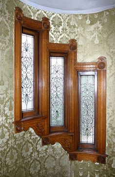 an ornate wooden window in a green wall