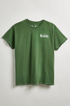 Modelo Cheers graphic tee. Classic cotton jersey tee in a standard fit is topped with Modelo graphics at the left chest and back, ribbed crew neck and short sleeves. Urban Outfitters exclusive. Features Model Cheers graphic tee Front and back graphics Regular fit Ribbed crew neck Short sleeves UO exclusive Content + Care 100% Cotton Machine wash Imported Size + Fit Model is 6’3" and wearing size Medium Measurements taken from size Medium Chest: 24" Length: 26" | Modelo Cheers Tee in Sage, Men's at Urban Outfitters Green Crew Neck T-shirt With Back Print, Green Relaxed Fit T-shirt With Back Print, Urban Outfitters Relaxed Fit T-shirt For Streetwear, Green T-shirt With Back Print In Relaxed Fit, Relaxed Fit Green T-shirt With Back Print, Green Graphic Tee With Back Print, Green Cotton T-shirt By Urban Outfitters, Relaxed Fit Graphic T-shirt From Urban Outfitters, Urban Outfitters Streetwear T-shirt With Screen Print