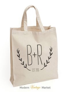 a tote bag with the initials and date printed on it, sitting against a white background