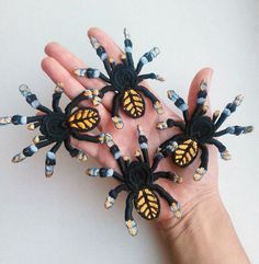 four small black and yellow spider brooches in the palm of someone's hand