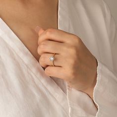 a woman wearing a diamond ring on her left hand and holding onto the back of her shirt