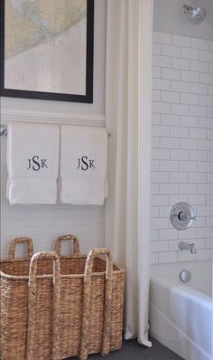 a bathroom with two towels hanging on the wall and three baskets in front of it