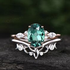 a ring with an oval cut green stone surrounded by white diamonds on a piece of wood