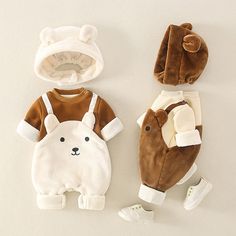 three baby clothing items are laid out on the floor, including one bear onesuit