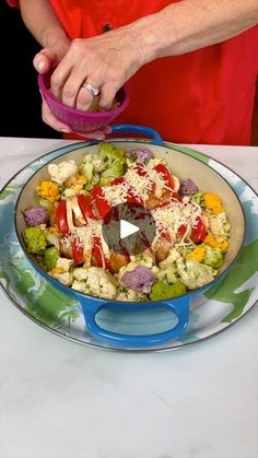 a woman is preparing a colorful salad with broccoli, cauliflower and tomatoes