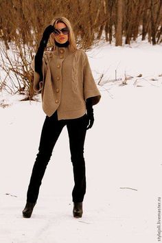 a woman standing in the snow with her hands on her head and wearing a sweater