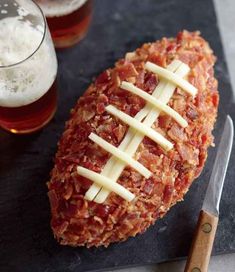 a piece of meat covered in cheese next to a glass of beer