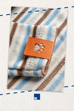 an orange tag is attached to a blue and white striped shirt with a dog paw on it