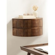 a round wooden shelf with books and glasses on it next to a desk in a room