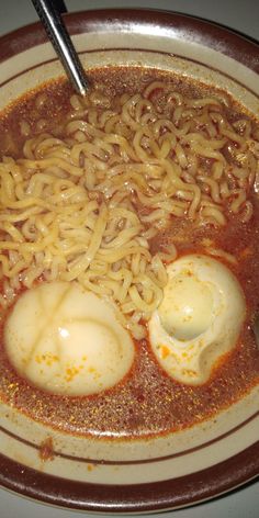 a bowl filled with noodles and eggs on top of a table