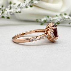 a close up of a ring on a table with flowers in the background and a white rose behind it