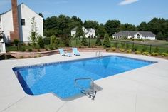 an empty swimming pool with lounge chairs around it and a fenced in yard behind it