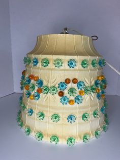 a lamp that is sitting on top of a white surface with blue and green flowers