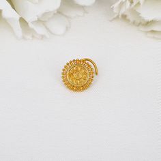 a close up of a brooch with flowers in the background and a white flower