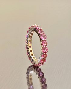 a pink and purple ring sitting on top of a white table next to a mirror