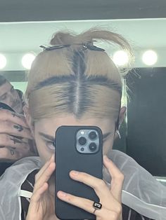 a woman taking a selfie in front of a mirror with her hair styled into a pony tail