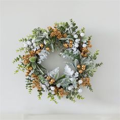 a christmas wreath with gold and white decorations on the front, surrounded by greenery