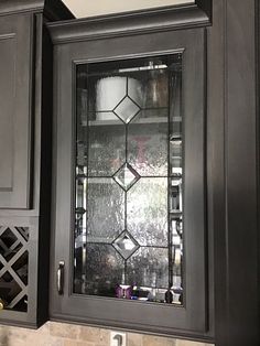 a glass cabinet door in a kitchen with marble counter tops and dark wood cupboards