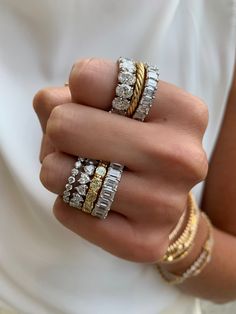 a woman's hand with three different rings on her fingers and two gold bracelets