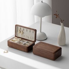 an open jewelry box sitting on top of a table next to a vase and lamp