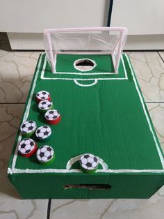 cupcakes are placed on top of a green box with soccer balls in it