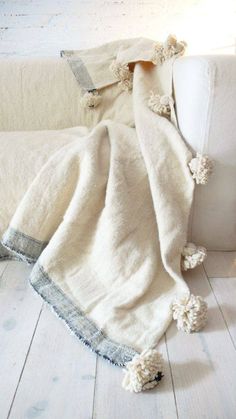 a white couch covered with a blanket and pom - poms on the floor