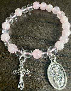 "Item details Handmade Materials Gemstone: 8mm Rose Quartz, Clear Quartz, Our Lady of Perpetual Help Medal, small ornate cross, Durable high quality stretch cord Rosary Bracelet for Women Stretch Bracelets, Our Lady of Perpetual Help, and small cross  The size of the bracelet is 7 inches.  May  request for a bigger or smaller size but there bead size will change. This will be a great gift for confirmation!  A unique and beautiful personalized rosary bracelet!  It will make a perfect religious themed gift or inspiration for yourself. The beads used on every piece are handpicked. We make sure that each bracelet includes a range of the natural colors found in the stone It is not guaranteed to look exactly the same as shown in pictures but we promise it will be just as pretty! To find your per Affordable Pink Rosary Bracelet For Gift, Spiritual Cross Charm Bracelet Gift, Pink Spiritual Jewelry With 8mm Beads, Pink Round Rosary Bracelet Gift, Spiritual Rose Quartz Jewelry With 8mm Beads, Adjustable Pink Cross-shaped Jewelry, Pink 8mm Bead Spiritual Rosary Bracelet, Pink Spiritual Rosary Bracelet With 8mm Beads, Adjustable Pink Rosary Bracelet For Healing