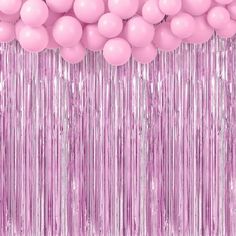 pink balloons and streamers are hanging in front of a wall with shiny foil fringes