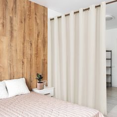 a bedroom with wood paneling and white curtains on the windowsill, along with a bed