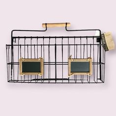 a metal cage with two small pictures hanging on it's sides and a wooden stick sticking out of the top