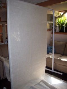 a living room with a couch, chair and white curtain on the wall in front of it