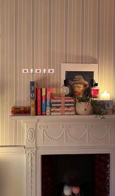 a fireplace with candles, books and pictures on it