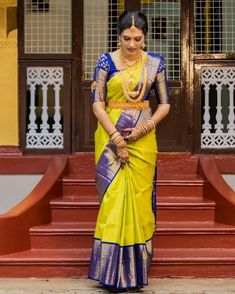 a woman in a yellow and blue sari standing on steps with her hands behind her back