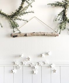 some white stars are hanging on the wall next to a branch and other decorations in front of it