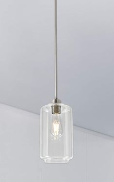 a glass light fixture hanging from the ceiling in a room with white walls and flooring